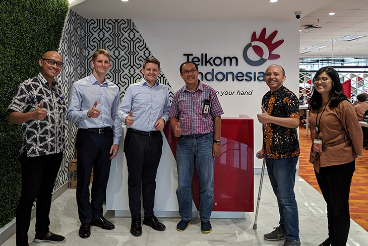 People standing in front of a Telkom indonesia logo