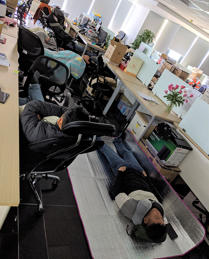 Office workers sleeping at the office on their chairs and on the floor